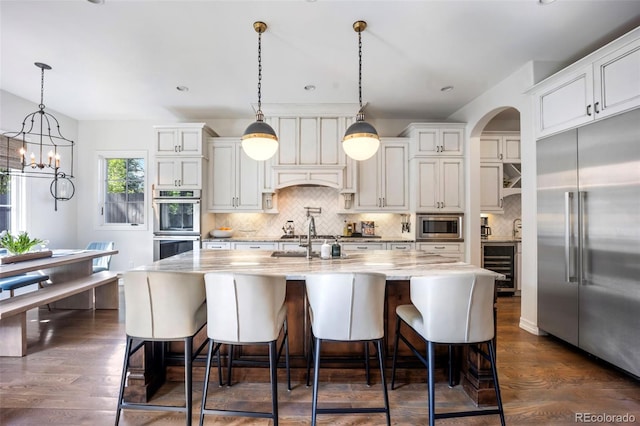 kitchen featuring built in appliances, decorative backsplash, dark wood-style floors, and beverage cooler