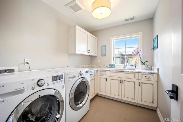 clothes washing area with cabinet space, visible vents, washing machine and dryer, and a sink