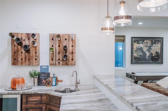 bar with beverage cooler, a sink, hanging light fixtures, and indoor wet bar