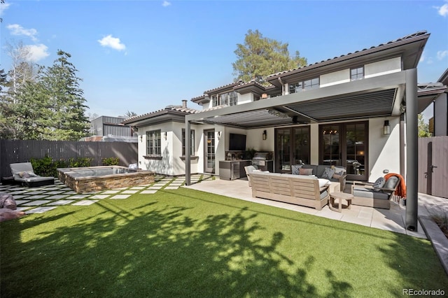 back of property featuring a fenced backyard, a lawn, stucco siding, and an outdoor living space