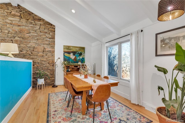 dining room featuring vaulted ceiling with beams, light wood-style floors, visible vents, and baseboards