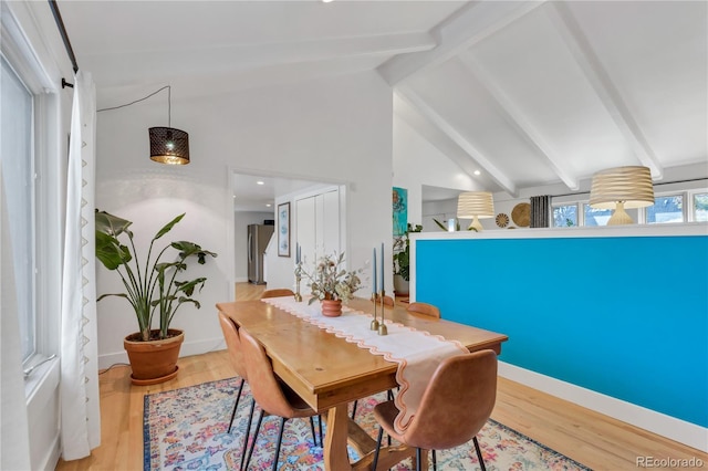 dining area featuring beamed ceiling, wood finished floors, baseboards, and high vaulted ceiling