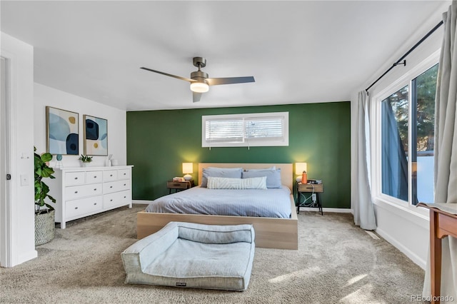 carpeted bedroom featuring baseboards, multiple windows, and ceiling fan