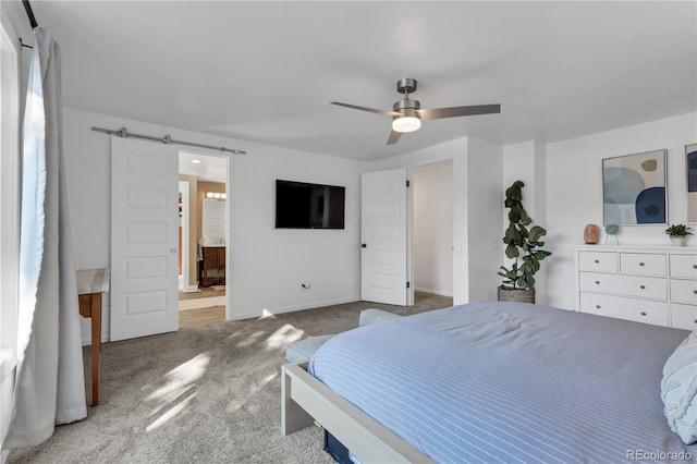 bedroom featuring connected bathroom, a barn door, carpet, baseboards, and ceiling fan