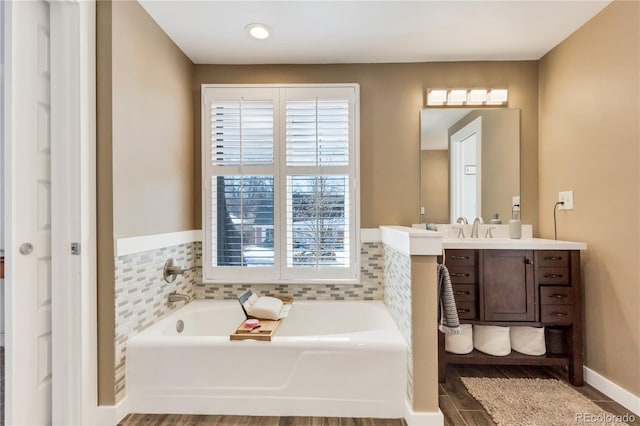 bathroom featuring baseboards, vanity, and a garden tub