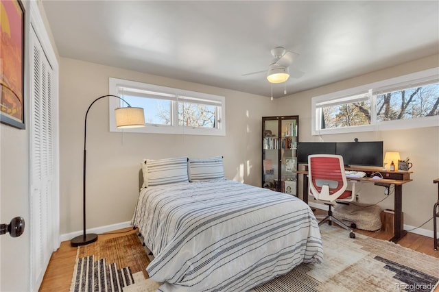 bedroom featuring a closet, baseboards, light wood-style flooring, and a ceiling fan