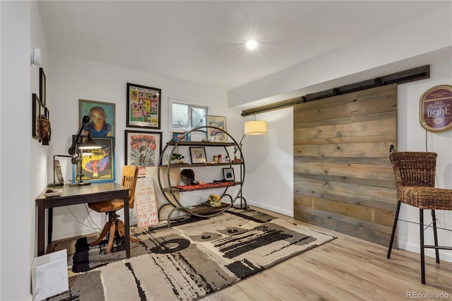 misc room featuring a barn door, wood finished floors, and baseboards