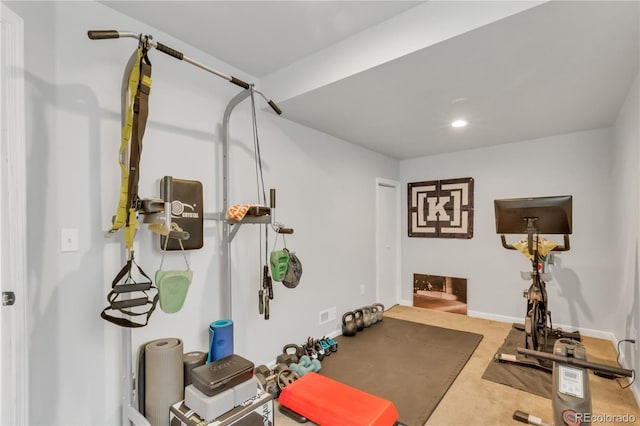 exercise room with baseboards and carpet floors