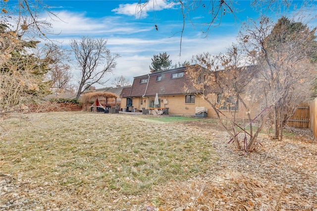 rear view of property with a patio area, a lawn, mansard roof, and fence