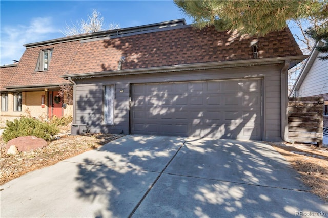 view of front of home with mansard roof, a garage, driveway, and a shingled roof