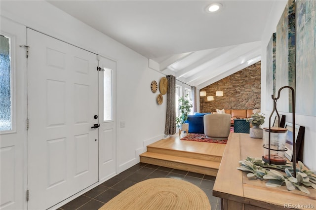 entrance foyer with lofted ceiling, dark tile patterned flooring, and baseboards