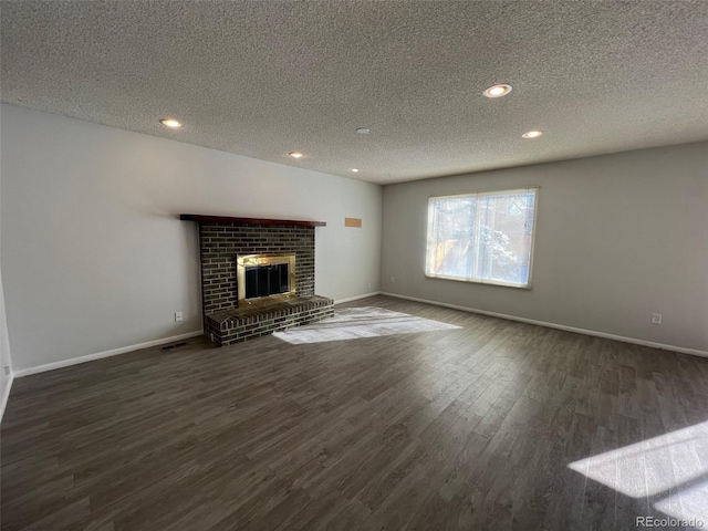 unfurnished living room featuring dark wood-type flooring, a brick fireplace, and a textured ceiling