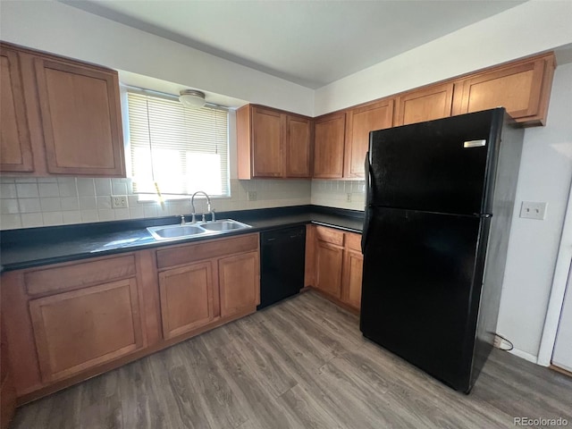 kitchen with sink, black appliances, hardwood / wood-style flooring, and backsplash