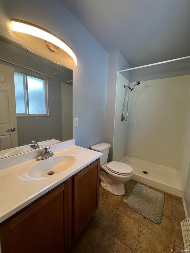 bathroom featuring tile flooring, toilet, a shower, and vanity