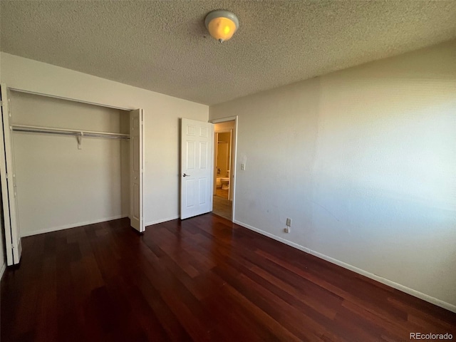 unfurnished bedroom featuring dark hardwood / wood-style flooring, a textured ceiling, and a closet