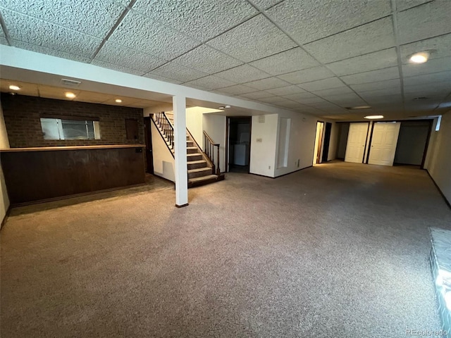 basement featuring a paneled ceiling and dark carpet