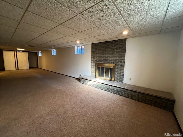 basement with a paneled ceiling, carpet, and a fireplace