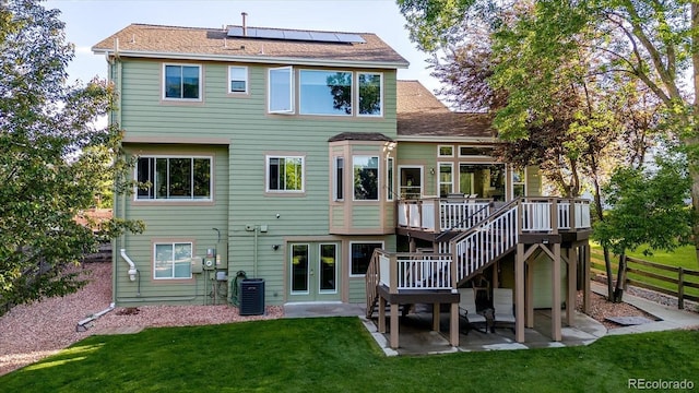 6266 Holman St, Arvada, CO 80004 - rear view of property with central air condition unit, a deck, a patio area, roof mounted solar panels, and stairway
