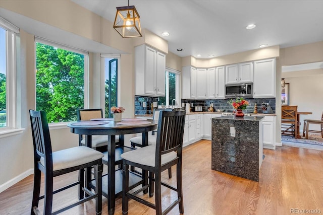 6266 Holman St, Arvada, CO 80004 - kitchen with stainless steel microwave, plenty of natural light, light wood-style flooring, a kitchen island, and recessed lighting