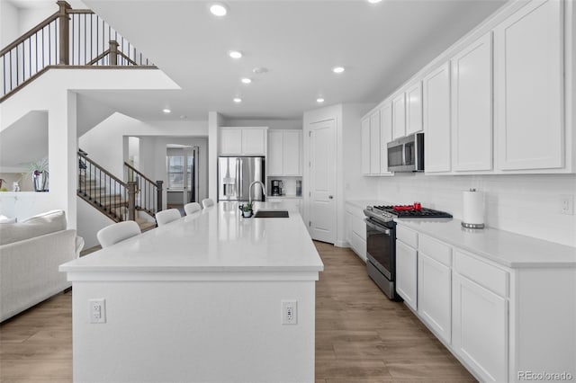 kitchen featuring white cabinets, stainless steel appliances, light wood-type flooring, and a sink