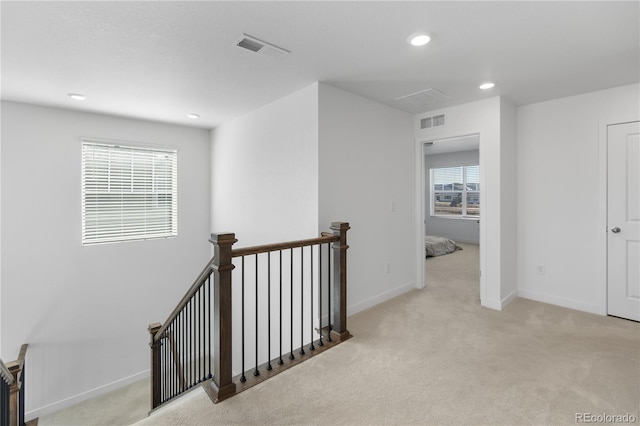 corridor with visible vents, an upstairs landing, and carpet floors