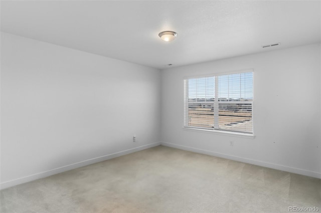 empty room featuring visible vents, baseboards, and light colored carpet