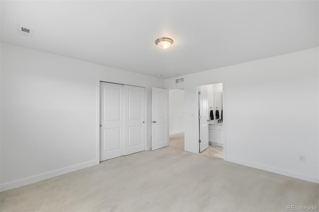 unfurnished bedroom with visible vents, a closet, connected bathroom, baseboards, and light colored carpet