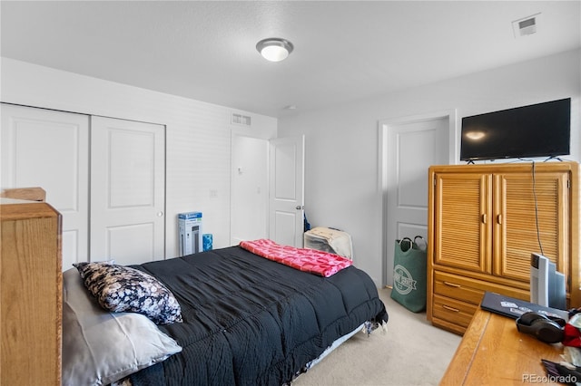 bedroom with visible vents, light carpet, and a closet