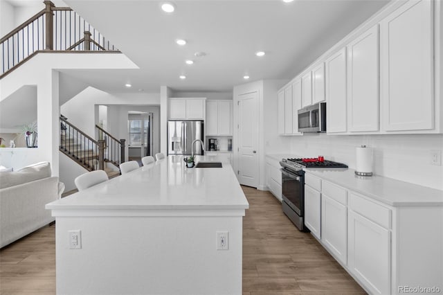 kitchen with recessed lighting, white cabinetry, stainless steel appliances, and a sink
