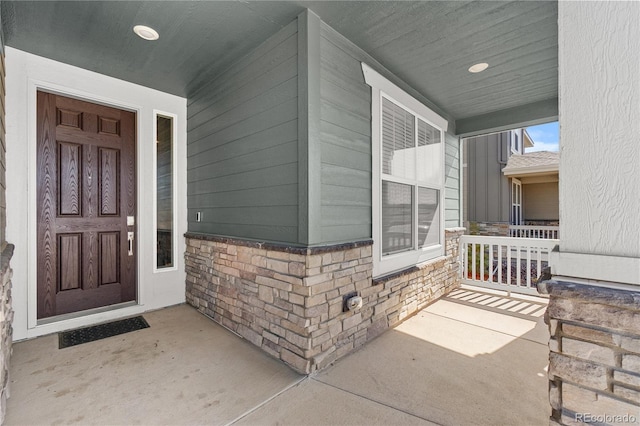 view of exterior entry with stone siding and covered porch
