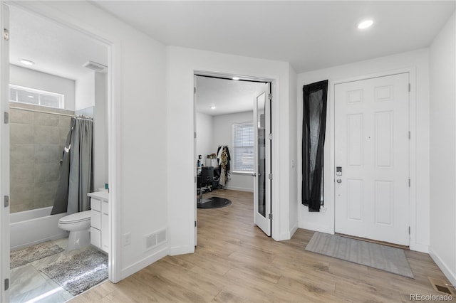 foyer entrance featuring baseboards, visible vents, and light wood finished floors