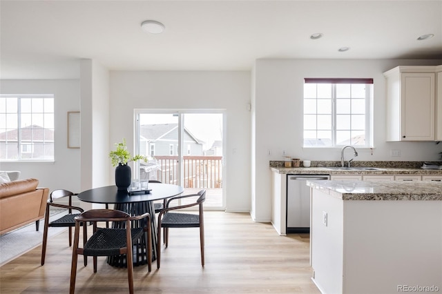 kitchen featuring a healthy amount of sunlight, sink, white cabinetry, and light hardwood / wood-style flooring