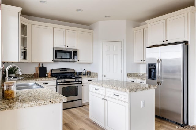 kitchen with light hardwood / wood-style floors, appliances with stainless steel finishes, sink, and a center island