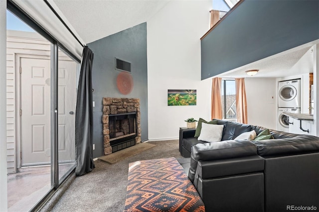 living room featuring visible vents, high vaulted ceiling, a fireplace, stacked washer and dryer, and carpet flooring