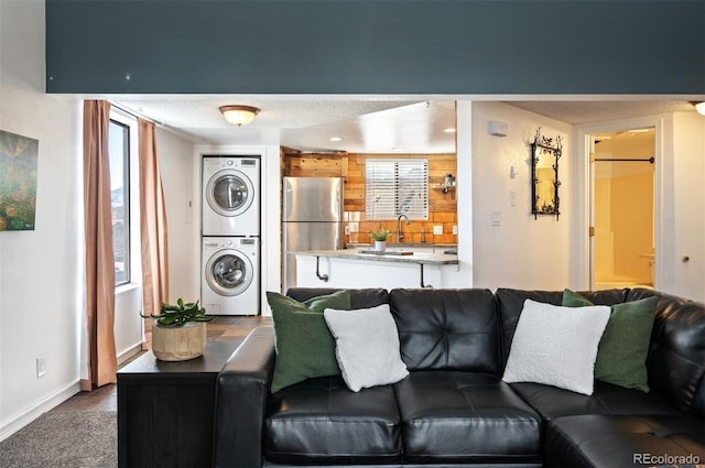 living room featuring dark wood finished floors, baseboards, stacked washer / drying machine, and a wealth of natural light