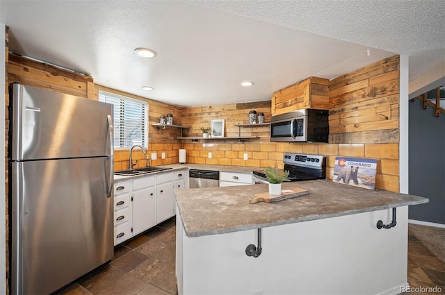 kitchen featuring a sink, open shelves, appliances with stainless steel finishes, a peninsula, and white cabinets