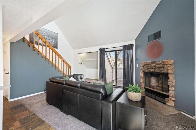 living room featuring visible vents, stairs, lofted ceiling, a stone fireplace, and a textured ceiling