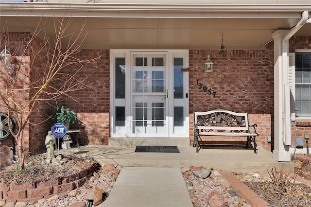 doorway to property with brick siding and a porch