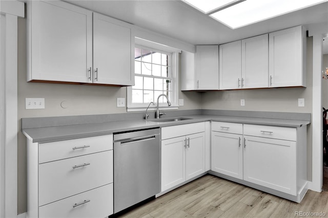 kitchen featuring dishwasher, light wood finished floors, a sink, and white cabinetry