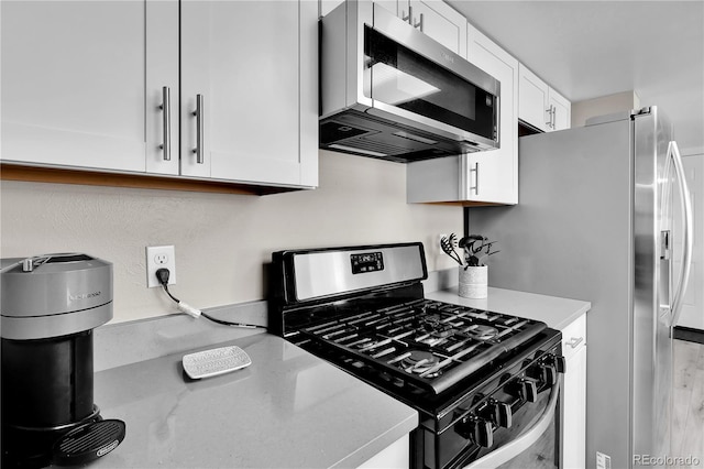 kitchen featuring stainless steel appliances, white cabinets, and light stone counters