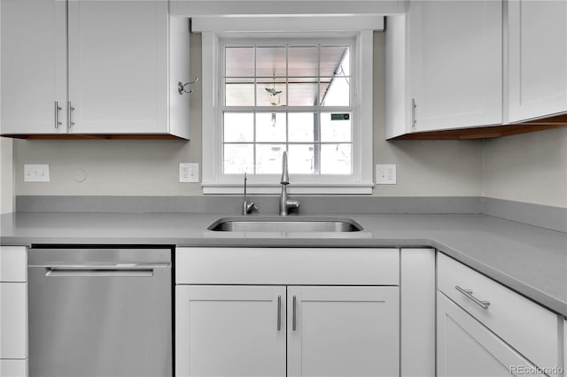 kitchen with light countertops, white cabinets, dishwasher, and a sink