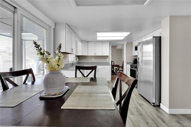 dining space with light wood finished floors and baseboards