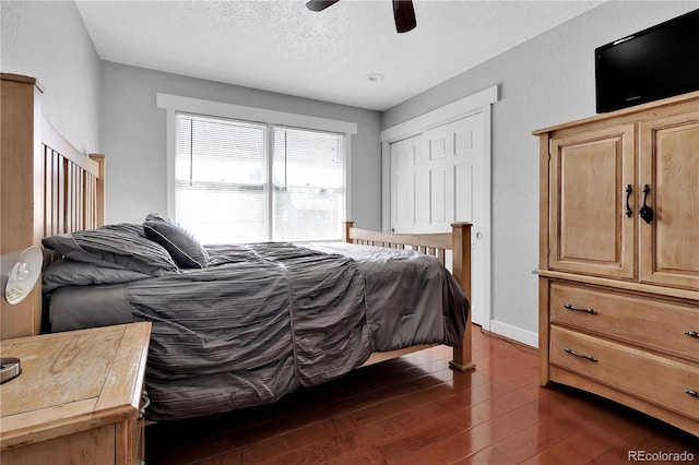 bedroom featuring baseboards, a ceiling fan, dark wood-style flooring, a textured ceiling, and a closet