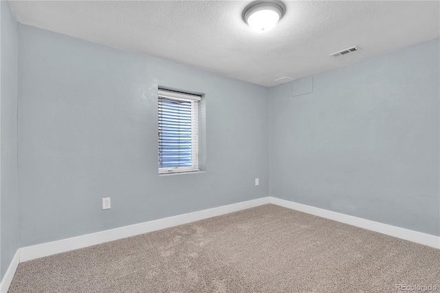 carpeted empty room featuring a textured ceiling, visible vents, and baseboards