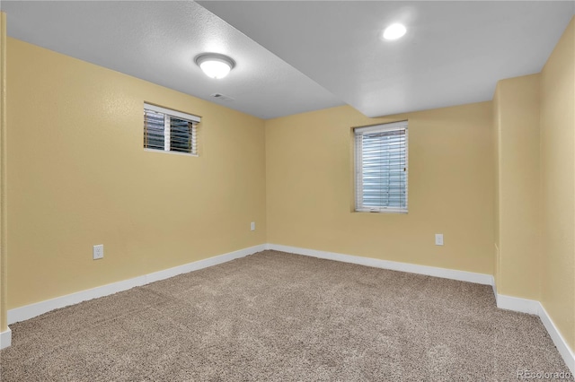 carpeted empty room featuring a textured ceiling, visible vents, and baseboards