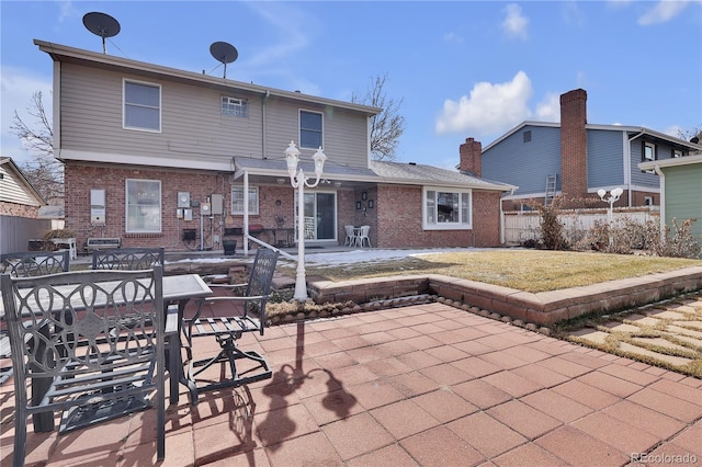 rear view of property featuring a patio area, brick siding, fence, and a lawn