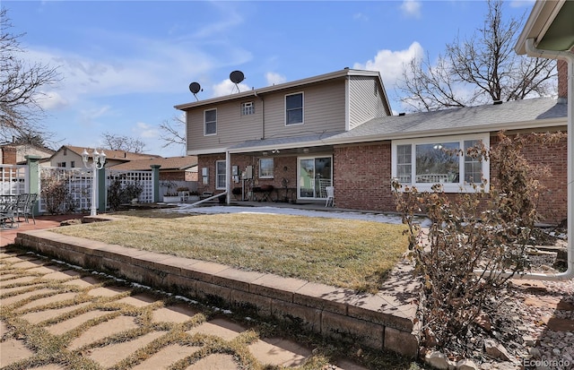 rear view of property with a patio area, brick siding, fence, and a lawn