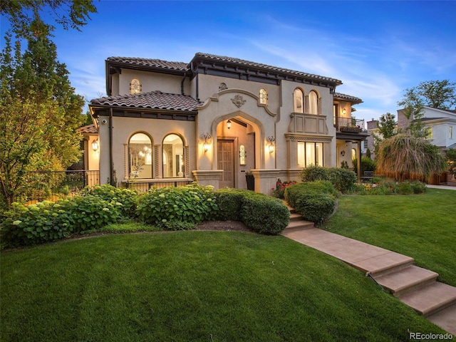 mediterranean / spanish-style home with a balcony and a yard