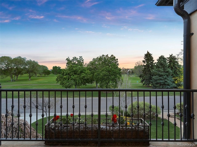 balcony at dusk featuring a water view