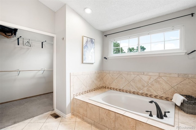 8288 W Chestnut Ave, Littleton, CO 80128 - full bathroom featuring a garden tub, a spacious closet, a textured ceiling, and tile patterned floors